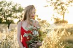 beautiful-woman-in-red-dress-holding-flowers-in-field-EIF01878.jpg